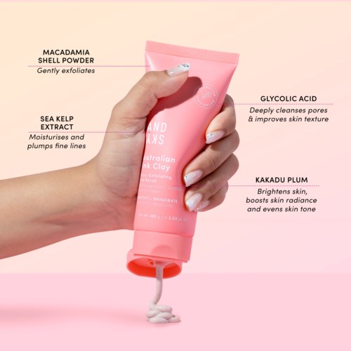 Eine Hand hält eine rosa Hautpflege-Tube mit der Aufschrift 'Australian Pink Clay'. Sie enthält Inhaltsstoffe wie Macadamia-Schale, Meereskellextrakt, Glycolsäure und Kakadu-Pflaume.