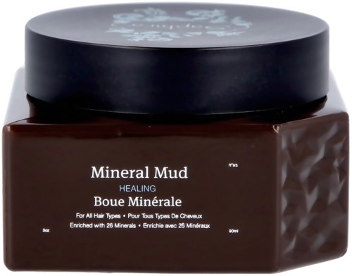 Een bruine pot met 'Mineral Mud Healing' voor haar, verrijkt met 26 mineralen, in een zwart deksel container.