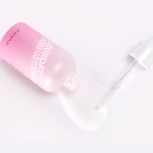Een roze fles met een pipet ligt op een witte ondergrond.