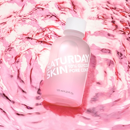 Roze huidverzorgingsfles met 'SATURDAY SKIN' en 10% glycolic pore control, drijft in roze water.
