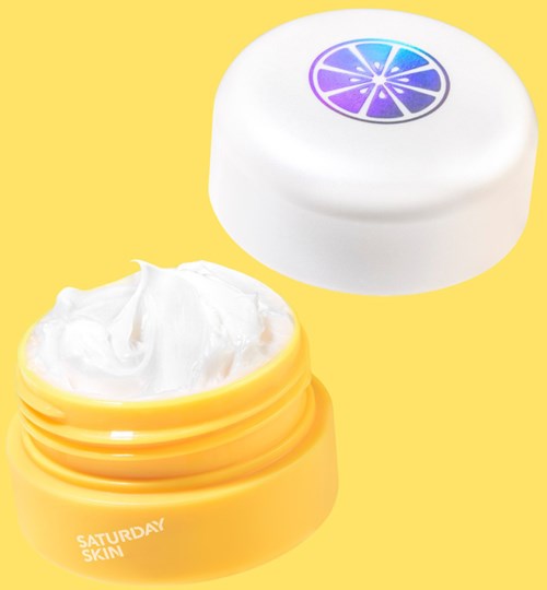Gele pot met witte crème, deksel met een paarse citroenschijf ontwerp, gemarkeerd 'Saturday Skin'.
