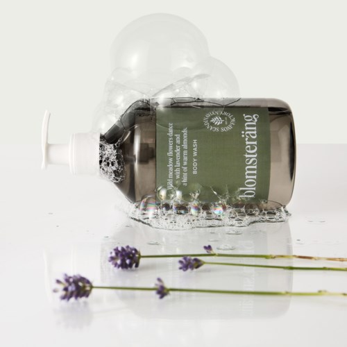 A bottle labeled 'blomsteráing' with soap suds and purple lavender flowers.