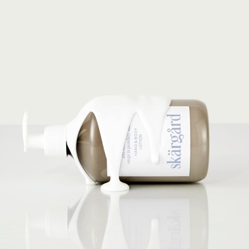 En flaska Skargård body lotion med vit lotion som spillts ut. Flaskan ligger på en vit yta, mest på sidan.