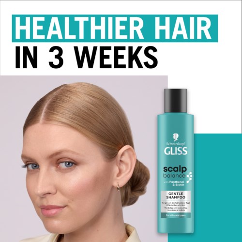 Een vrouw met schoon, glanzend haar naast een turquoise shampoo fles, zelfverzekerd glimlachend.