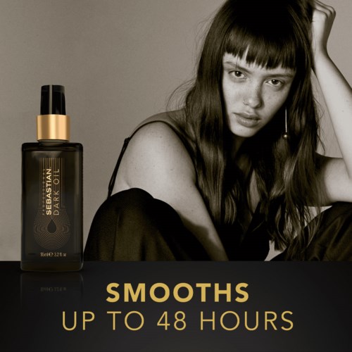 Zwart-wit foto van een vrouw met lang haar die naast een donkere fles huidverzorgingsproduct zit. Tekst zegt 'Smooths up to 48 hours.'