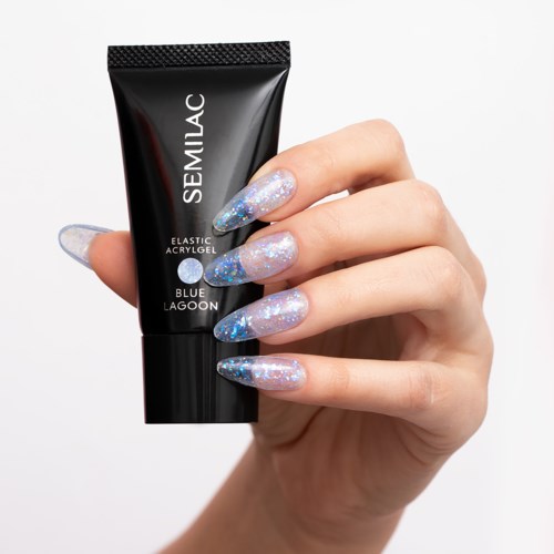 Hand mit langen, glitzernden, blauen und silbernen Nägeln, die eine schwarze Tube mit Semilac Nagelgelle halten.