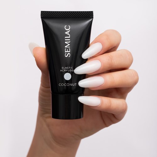 Hand holding black tube of SEMILAC nail gel with white nails. One nail painted, others are plain.