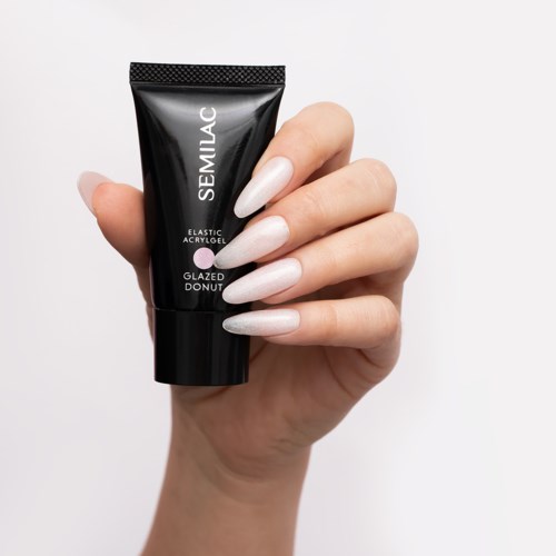 A hand with white, long nails holding a small black tube labeled 'SEMILAC'.