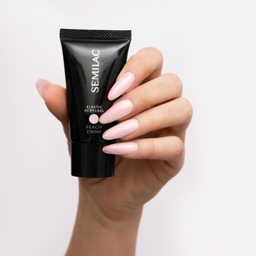 A hand holds a black tube of Semilac adhesive with light pink nails, against a plain white background.