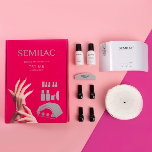 Ein pinker Karton mit Nagellackflaschen, UV-Lampe und Schwamm für Maniküren.