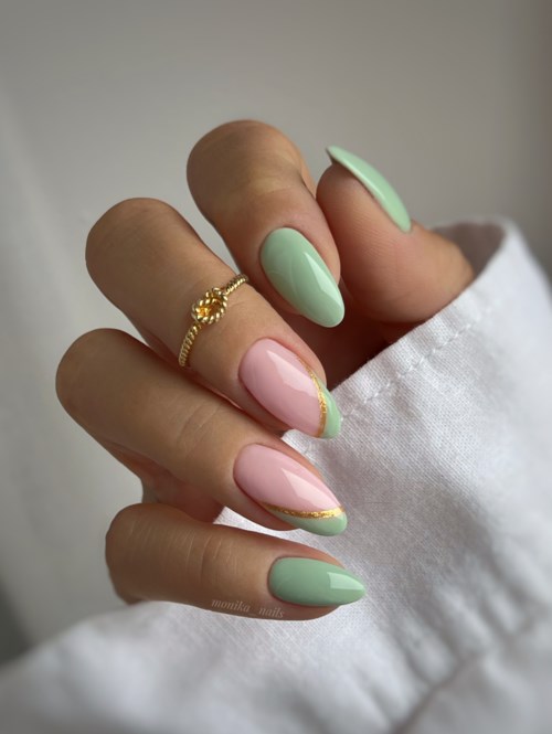 Hand with decorated nails and a gold ring on one finger, wearing a white sleeve.