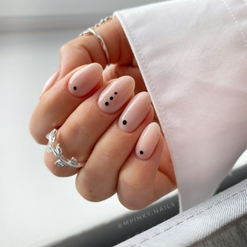 Hand mit schön lackierten Nägeln mit kleinen schwarzen Punkten, hält einen weißen Ärmel. Eleganter und einfacher Stil.