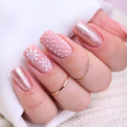 Pinkfarbige und glitzernde Nägel mit weißen Schneeflocken und texturierten Mustern. Die Nägel sind lang und winterlich dekoriert.