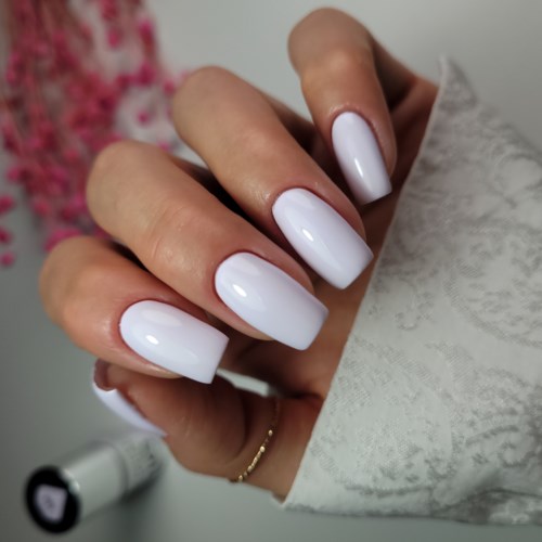 A hand with neatly painted white nails, partly covered by a white cloth, in a well-lit setting.