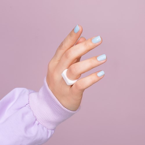 Eine Hand mit hellblauen Nägeln, trägt einen Ring, vor einem helllila Hintergrund.