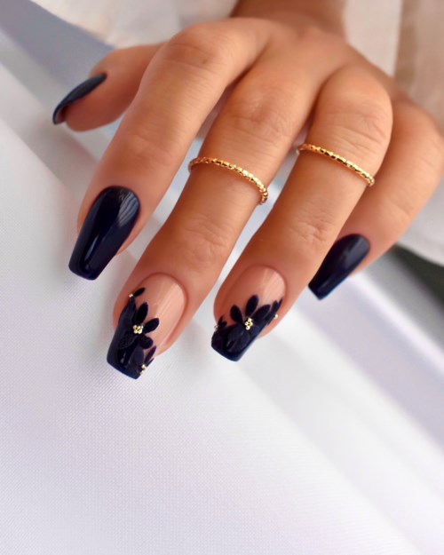 Hände mit schwarzen und nude Nagellack, und kleinen goldenen Ringen an zwei Fingern.