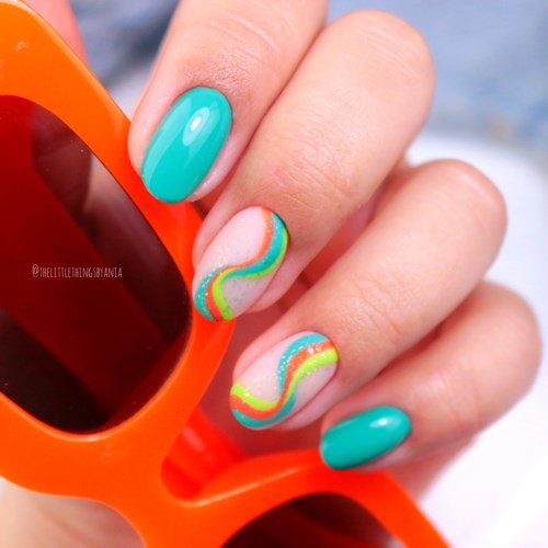 Nail art with colorful, swirling designs on light-colored nails, with one hand holding orange sunglasses.