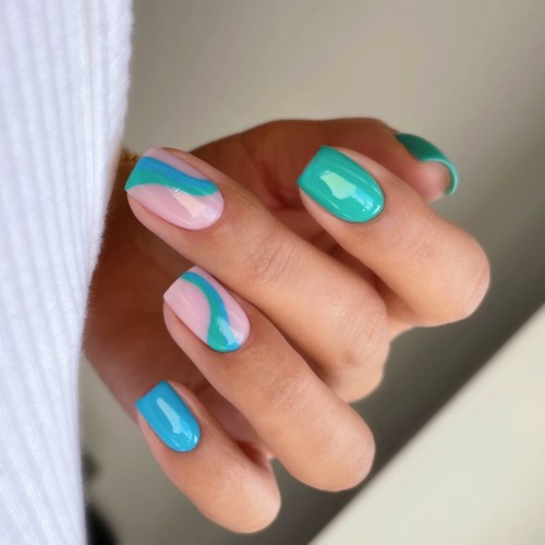 Farbenfrohes Nageldesign mit blauen, pinken und grünen Wellenmustern.