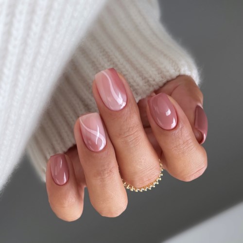 Hand mit gepflegten Nägeln und einem cremefarbenen Pullover, Finger leicht gekrümmt.