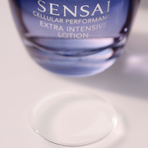Eine blaue Flasche Sensai-Lotion mit klarer Flüssigkeit, auf weißer Oberfläche.