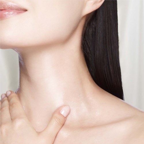 Eine Frau berührt sanft ihren Hals, zeigt glatte Haut und dunkle Haare. Blick auf Hals und Hand.