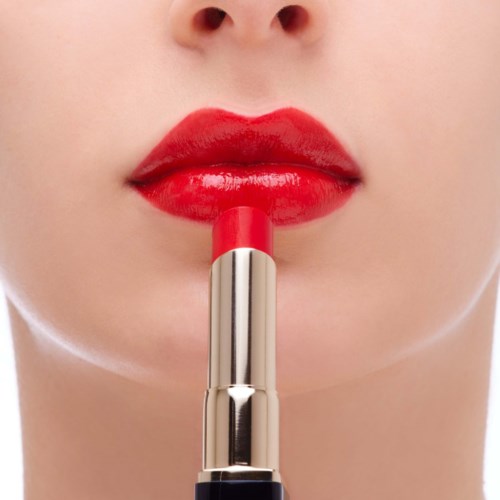 Close-up of lips being colored with red lipstick.
