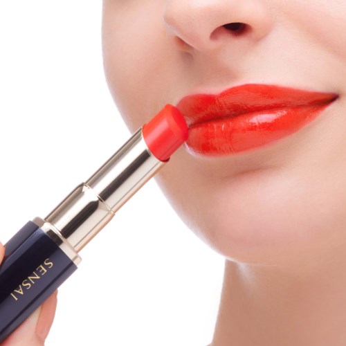 Eine Person trägt leuchtend roten Lippenstift auf.