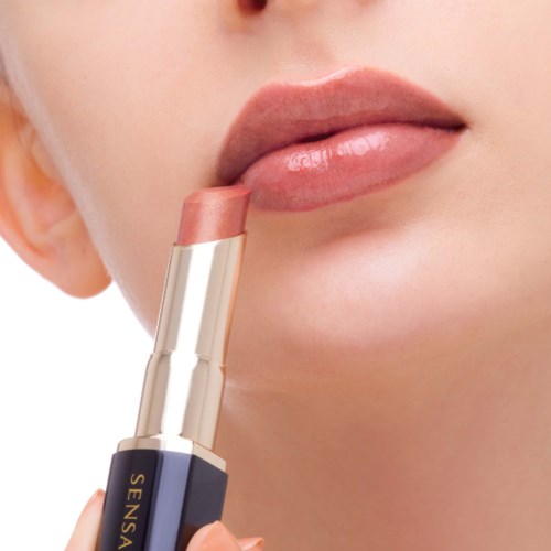 Eine Person trägt hellrosa Lippenstift auf.