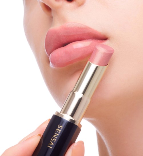 Eine Person trägt pinken Lippenstift auf ihre Lippen auf, Fokus auf Lippen und Lippenstift.