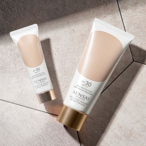Twee flessen zonnebrand met gouden deksels op tegels, één groot en één klein, met SPF 30.