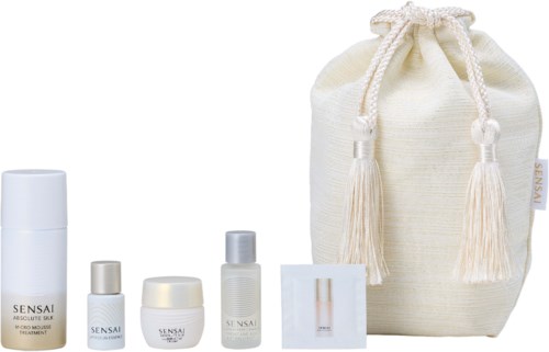 A set of skincare products and a cloth bag, all from Sensai, arranged neatly. The bag is cream-colored and tied with tassels.