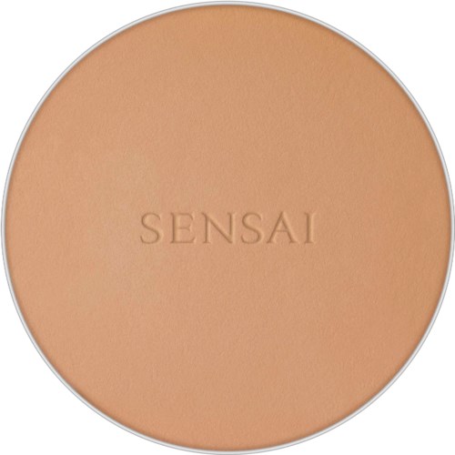 Eine runde Kompaktdose mit der Gravur "SENSAI" auf einer pfirsichfarbenen Oberfläche.