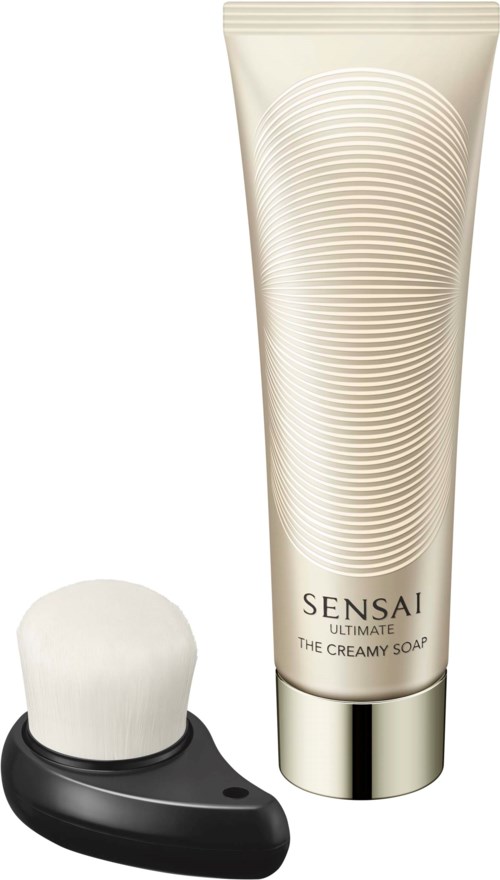 Eine Tube Sensai Ultimate cremige Seife und eine schwarz-weiße Gesichtsreinigungsbürste.