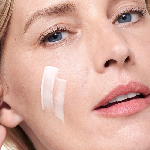 Nahaufnahme einer Frau, die Gesichtspflege aufträgt oder entfernt, mit klarer Haut und leichtem Make-up.