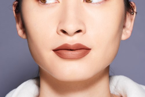 Närbild av en kvinnas ansikte med makeup, neutrala läppar och mjukt bakgrund.