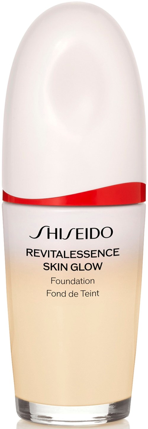 A tall, white bottle of Shiseido skincare product with a red stripe and cream-colored base.
