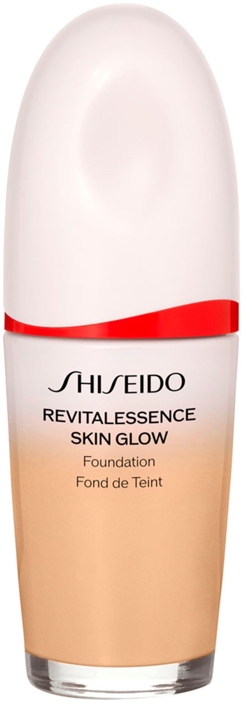 A foundation bottle with a white cap, beige liquid inside, and red and black text on the front.