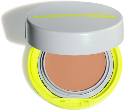 Ein runder Behälter mit hellgrauem Deckel, leuchtend gelben Seiten und beige Innen, enthält ein Kosmetikprodukt.