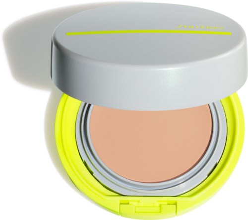 A compact with a bright yellow and gray design. It contains a cream or foundation product inside.