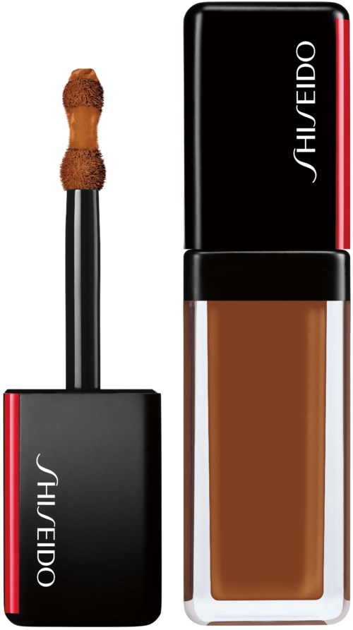 En Shiseido flytande foundationflaska med svart lock och röd rand, en svampapplikator på borsten.