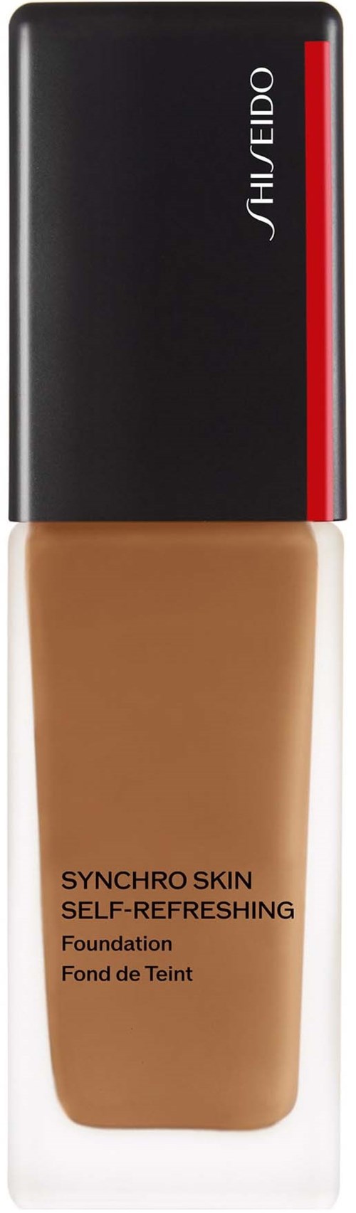 En flaska av Shiseido Synchro Skin-foundation med svart och rött lock och ljusbrunt innehåll.