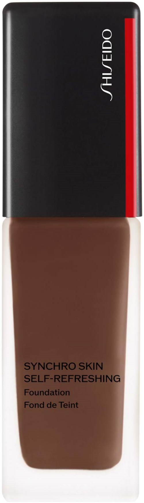En flaska av Shiseido Synchro Skin foundation, mörk beige färg, svart och röd kork, märkt som självuppfriskande.