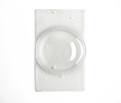 Ein klarer runder Linse auf einem weißen rechteckigen Sockel, minimalistisch und einfach im Design.