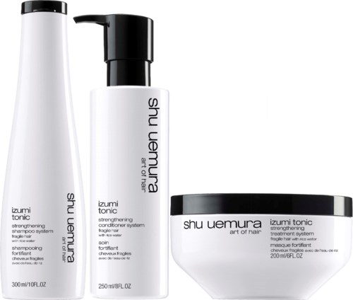 Three hair care products: shampoo, conditioner, and treatment, all labeled 'Shu Uemura Izumi Tonic' for strengthening hair.