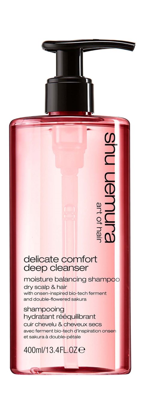 Eine rosa durchsichtige Flasche mit schwarzem Pumphals, beschriftet 'Shu Uemura Art of Hair'.