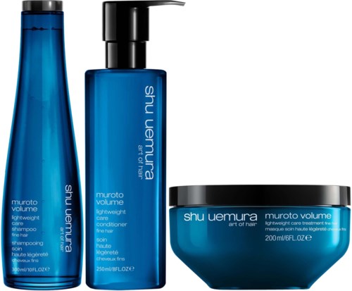 Three blue hair care products from Shu Uemura, including shampoo, conditioner, and a hair mask container.