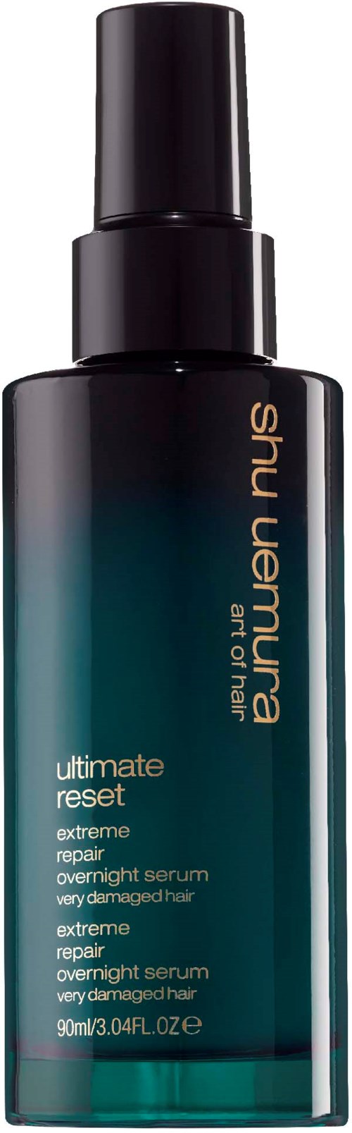 Een donker teal en zwarte fles met spray, gemerkt 'shu uemura', voor haarserum, genaamd 'ultimate reset'.