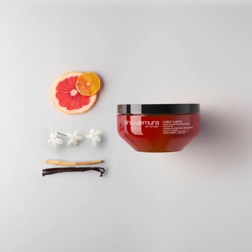 Een rode haarmaskerpot, gesneden grapefruit en sinaasappel, witte bloemen,vanillestok en een lichte achtergrond.