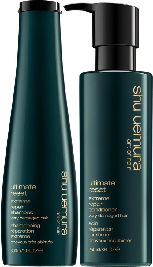 Twee donkergroene flessen haarverzorgingsproducten, waarvan één met een pomp, gelabeld "Shu Uemura Ultimate Reset" voor beschadigd haar.