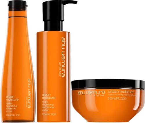 Drei orange Haarpflegeprodukte: Shampoo, Conditioner und Maske, mit schwarzen Deckeln und Etiketten.